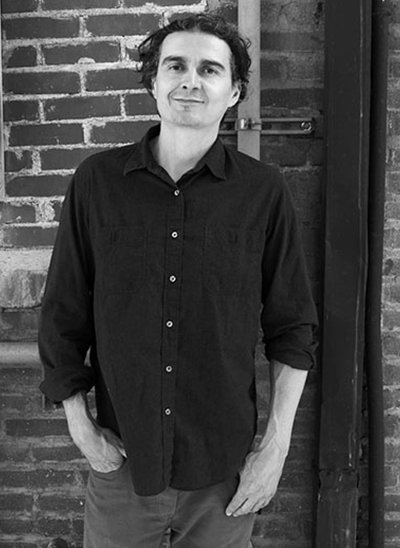 Man standing next to a brick wall.